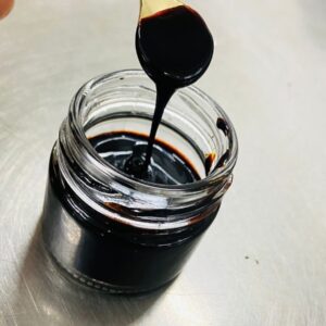 Pure Himalayan shilajit resin jar with measuring spoon on natural stone background