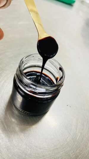 Pure Himalayan shilajit resin jar with measuring spoon on natural stone background